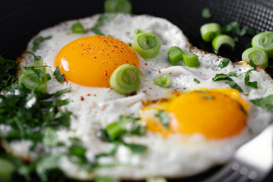 Fried eggs with vegetables on pan