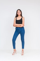 Front view of a young asian woman in a black bodysuit and jeans Isolated on a white background. Arms crossed near hips. Whole body photo.