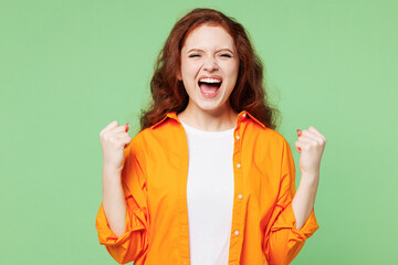 Young excited ginger woman she wear orange shirt white t-shirt casual clothes doing winner gesture...