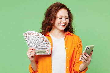Young ginger woman wear orange shirt white t-shirt casual clothes hold in hand fan of cash money in...
