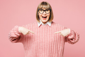 Elderly surprised shocked happy woman 50s years old wear sweater shirt casual clothes point index finger on herself isolated on plain pastel light pink background studio portrait. Lifestyle concept.