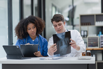 female African American doctor and doctor man working with examining x-ray reports at hospital.