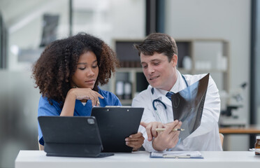 female African American doctor and doctor man working with examining x-ray reports at hospital.