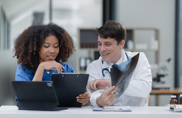 female African American doctor and doctor man working with examining x-ray reports at hospital.