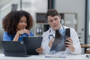 Obraz premium female African American doctor and doctor man working with examining x-ray reports at hospital.