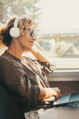Modern travel lifestyle people with happy smiling woman listening music with headphones and laptop...