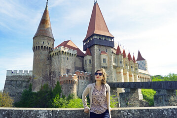 A female tourist stands in front of the Corvin Castle - the main attraction of the Romanian city of...