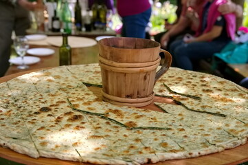 Soparnik - traditional Croatian food on big wooden plate with wooden mug in the middle