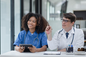 female African American doctor and doctor man working with clipboard in hospital.