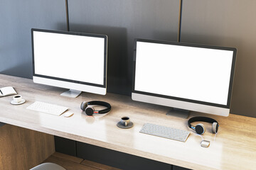 Two empty white gaming computer displays on desk with coffee cups and headsets. Place for your advertisement. Gaming club concept. Mock up, 3D Rendering.