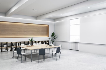A modern meeting room with a large table, chairs, and office shelving under indirect lighting,...