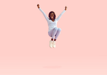 Happy young energetic African American woman in casual blue long sleeve shirt, skinny jeans and...