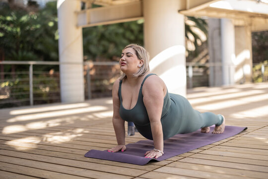Young woman with eyes closed practicing plank pose on mat