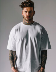 Obraz premium A tattooed man in an oversized white t-shirt poses for a full-body shot.