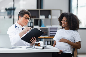 Fototapeta premium Male doctor examining a pregnant African American woman at the hospital.