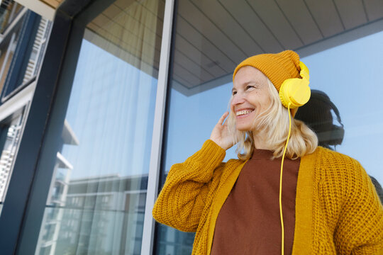 Happy woman enjoying listening to music through headphones