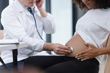 Obraz premium Male doctor examining a pregnant African American woman at the hospital.