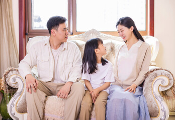 A family of three in the living room with their daughter reading and playing