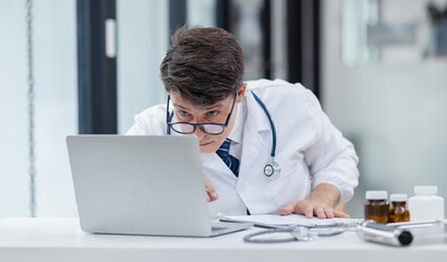 Doctor man working on laptop in the office of the clinic.