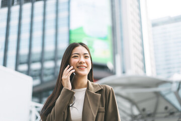 Asian business single woman using smart phone talking metropolis city background