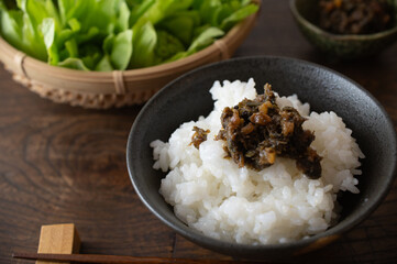 お茶碗に盛られた白ご飯とフキ味噌。木のテーブル