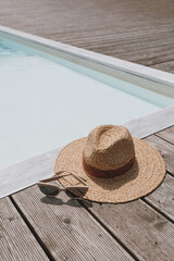 Relaxing, sunbathing at resort swimming pool. Straw hat, sunglasses at poolside. Summer vacation...