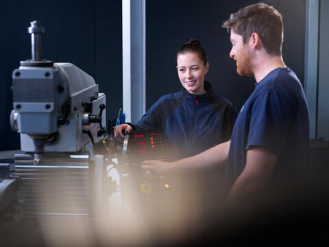Engineer explaining CNC machine to colleague at factory