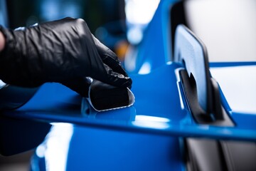 Car cash or car detailing studio worker applying graphene or ceramic coating on blue sport car. - 799869213