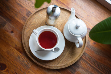 fruit tea cup, teapot and sugar bottle on round wood tray on wooden sill. tea time