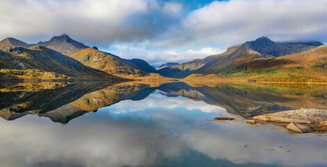beautiful mountainous landscape reflected on the water with clouds in the sky - svolvaer in Norway