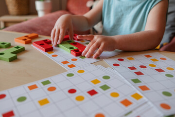Boy playing educational wooden game on table at home