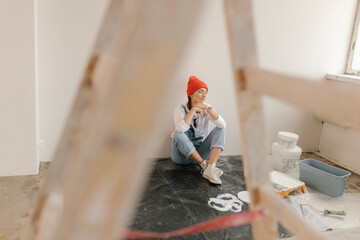Woman taking break sitting in front of white wall at home