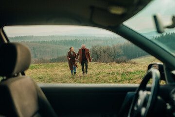 Happy senior couple enjoying vacations on mountain seen through car window