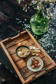 Fresh traditional Polish soup Zurek in bowl on wooden tray by vase with blossom