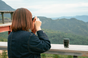 solo asian woman hipster traveler taking photo to mountain at outdoor bar of coffeeshop