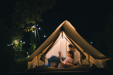 asian couple relax and reading book in camping tent on summer vacation
