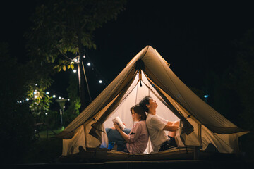 asian couple relax and reading book in camping tent on summer vacation