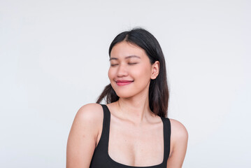 Young Asian woman in black bodysuit posing with eyes closed, isolated on white