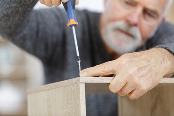 senior man working on a furniture - obrazy, fototapety, plakaty