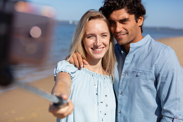 happy couple taking selfie with selfie stick at the beach - Powered by Adobe