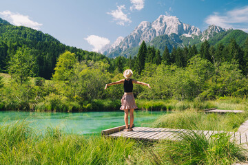 People in nature. Tourist woman with raised arms up in green nature background. View on Zelenci...