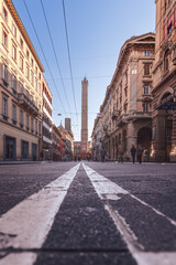 A low-angle perspective of a Bologna street, emphasizing the road lines converging towards the...