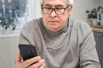 Hoary old man looking at web camera, holding phone, talking with children, wife online. Senior...