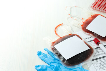 Bags and test tube with donor blood, document on light background, space for text