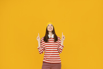 The girl points with her fingers, emphasizes attention, on a yellow background.