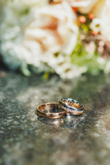 Precious gold rings for newlyweds on a background of flowers. Wedding rings for a couple.