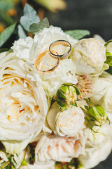 Precious gold rings for newlyweds on a background of flowers. Wedding rings for a couple.