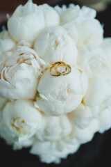 Precious gold rings for newlyweds on a background of flowers. Wedding rings for a couple.
