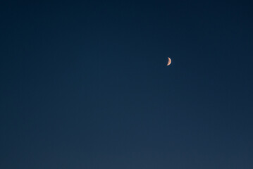 The moon in the sky. Real sky with little stars and a crescent. Amazing crescent moon on dark blue night sky background. Universe with noise and grain.selection focus.