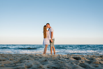 Female kiss and hugs male stand barefoot on beach ocean and enjoy sunny summer day on vacation....